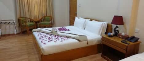 Habitación de hotel ordenada con una cama de madera, una mesita de noche con lámpara y dos sillones.
