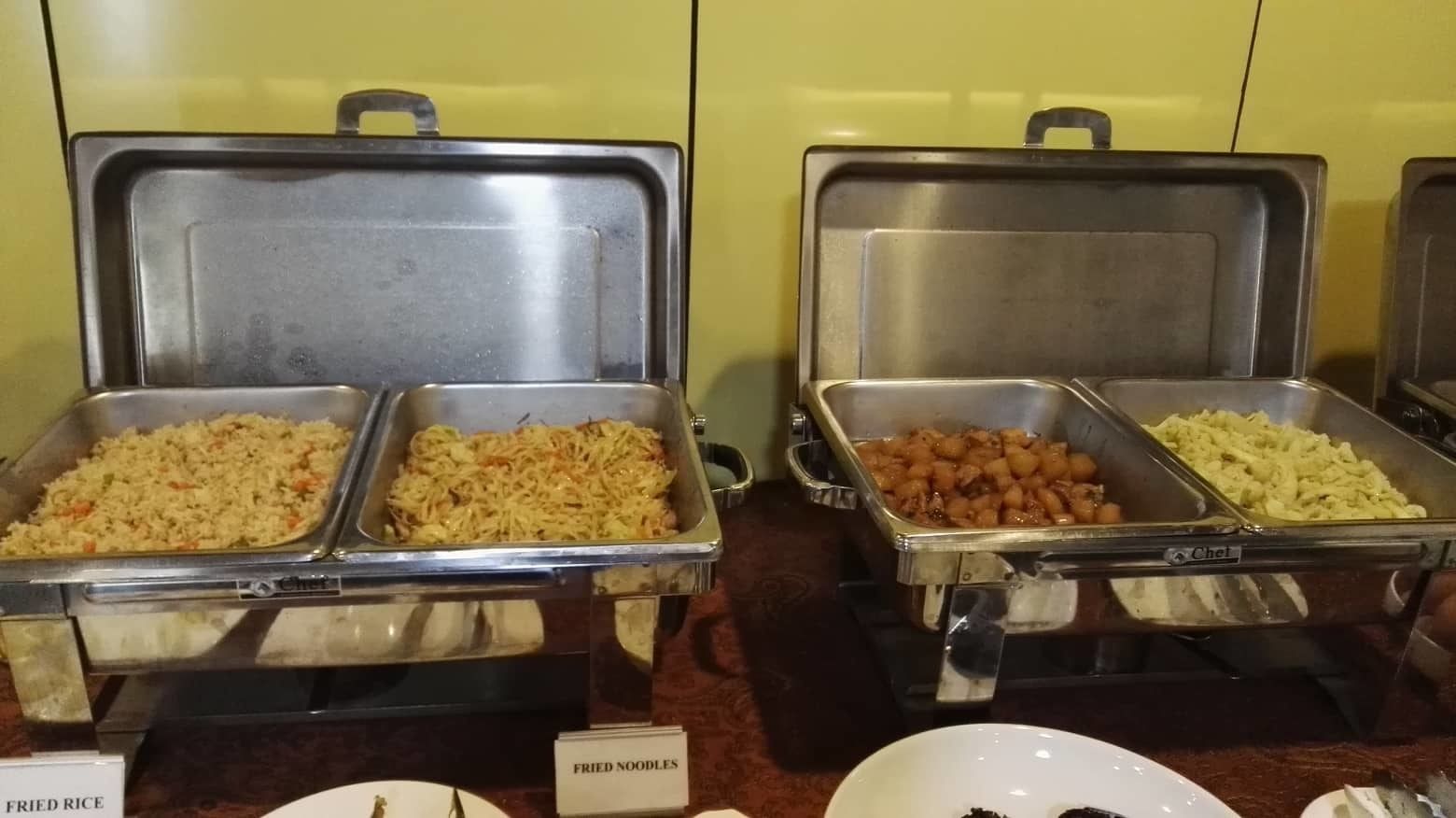 A buffet with labeled food items including fried rice, fried noodles, and other dishes.