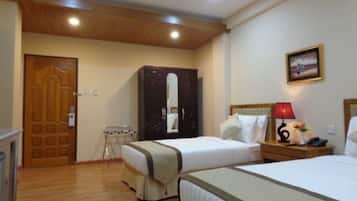 Une chambre d’hôtel avec deux lits, une armoire en bois, un miroir, une table de chevet avec une lampe et un tableau au mur.