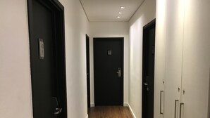 Un pasillo estrecho con suelo de madera, puertas negras y paredes blancas.