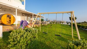 A children's play area with swings and slides, a wooden sauna, and a poolside seating area with umbrellas. - Tropical Sol (Kos)