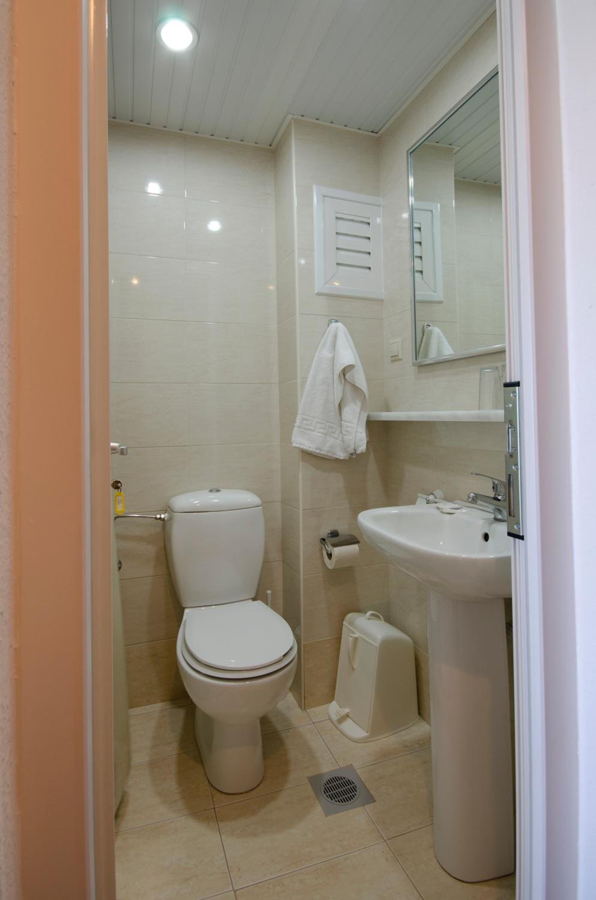 A small, clean bathroom with a toilet, sink, and mirror.