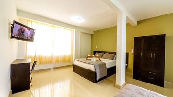 A hotel room with a bed, a desk, a television, and a wardrobe.