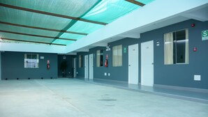 A spacious indoor area with a high ceiling, multiple doors, and emergency equipment. - Hostal Villa Santa (La Victoria)