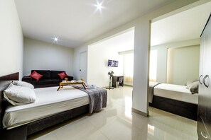 A modern hotel room with a large bed, a sofa, a desk, and a TV. - Hostal Villa Santa (La Victoria)