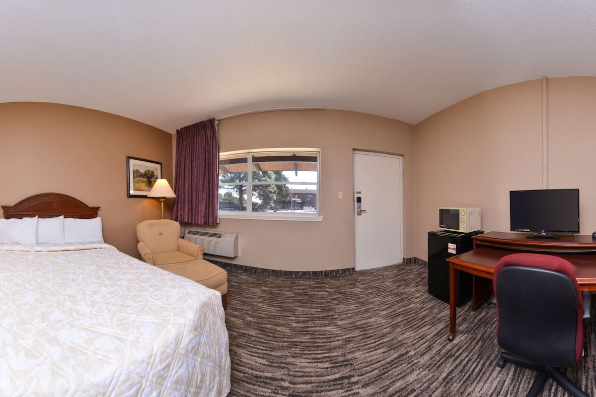 A hotel room with two beds, a desk, a chair, a TV, and a window with curtains.