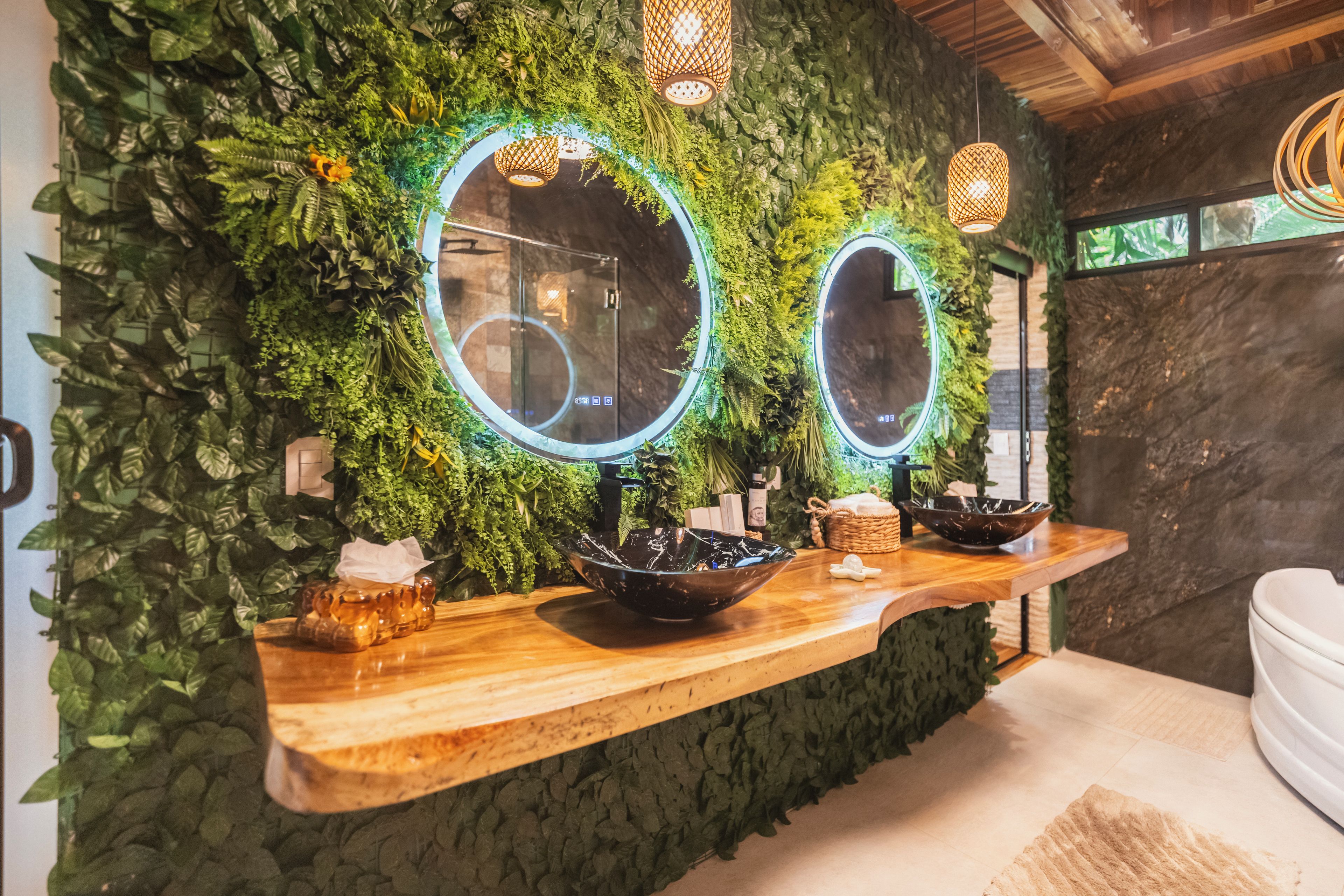 A bathroom with a green wall, two mirrors, and a wooden vanity with a bowl sink.