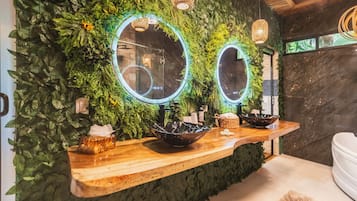A bathroom with a green wall, two mirrors, and a wooden vanity with a bowl sink.