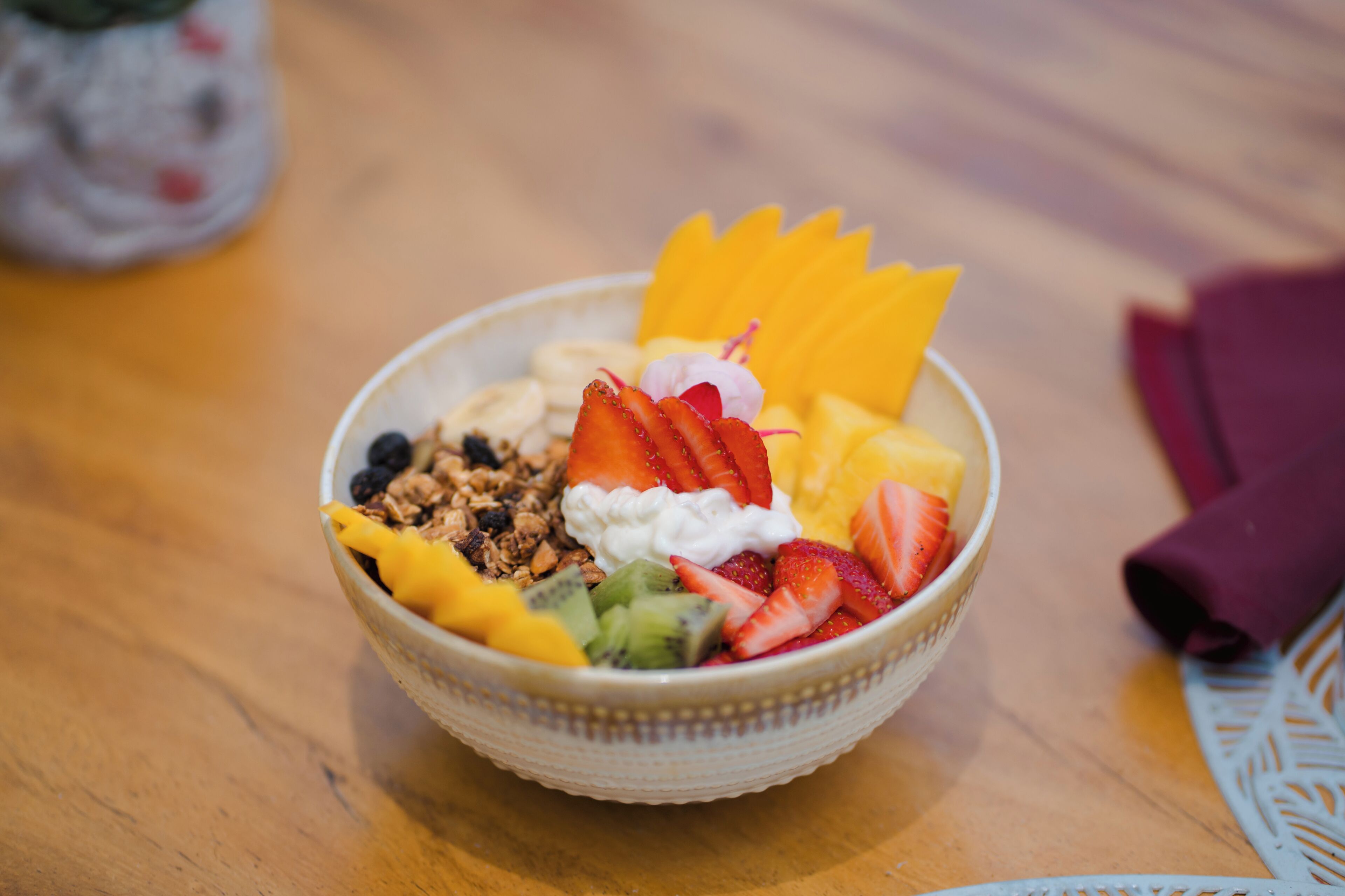 Un cuenco con fruta y yogur sobre una mesa de madera.