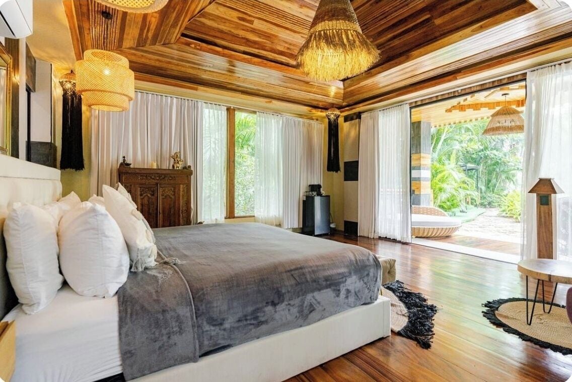 Ein geräumiges Schlafzimmer mit einem großen Bett, Holzboden und Blick ins Freie.