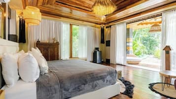 A spacious bedroom with a large bed, wooden ceiling, and a view of the outdoors.