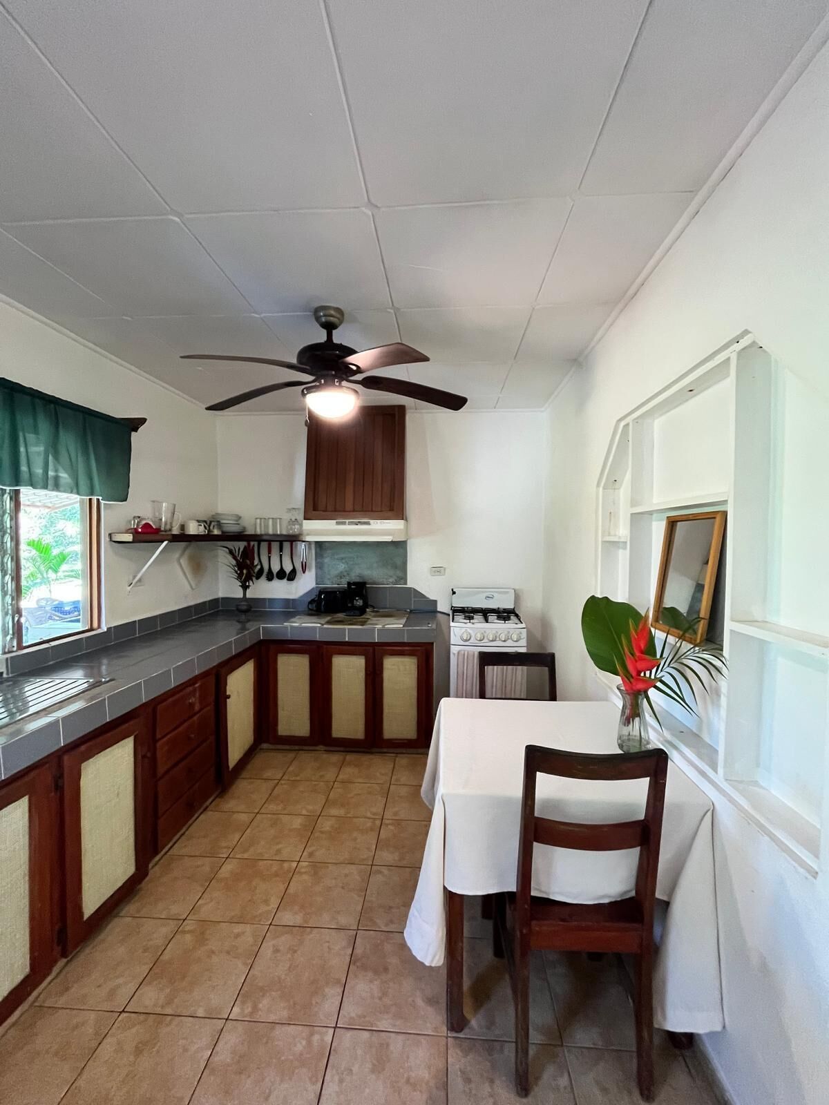 A kitchen with a dining table, a ceiling fan, and a window with a view.