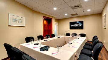 A conference room with a long table, chairs, a phone, and wine glasses.