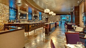 Zona de bar con varias opciones de asientos y una pantalla de televisión.