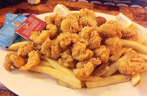 A plate of fried chicken and French fries with a packet of cocktail sauce.