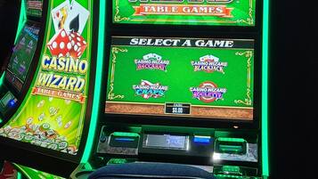 Una máquina tragamonedas de casino con una pantalla iluminada en verde y una pantalla de selección.