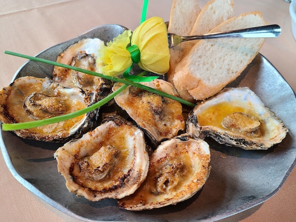 A plate of oysters with bread and a lemon on a table.