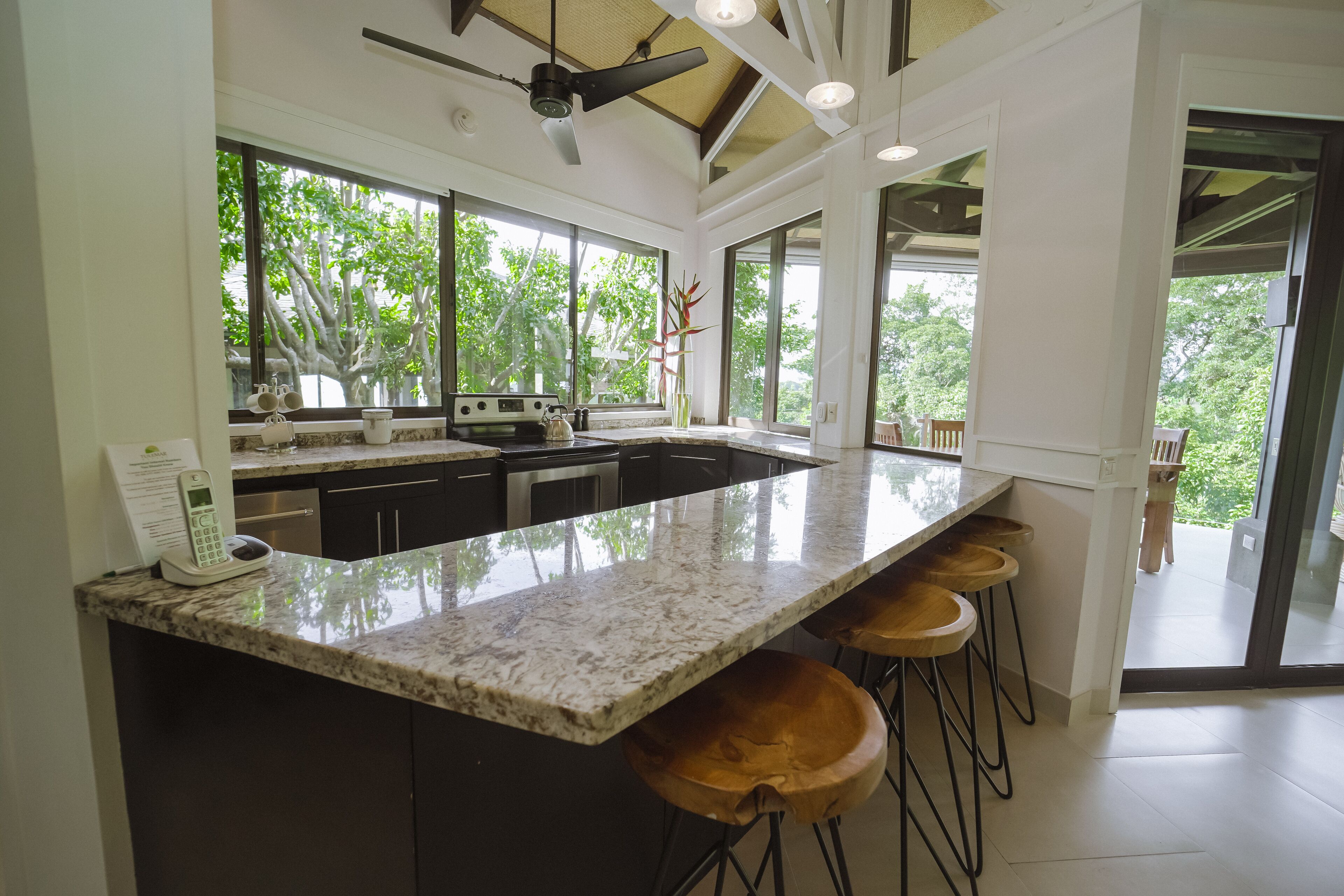 A modern kitchen with a large island, bar stools, and a view of the outdoors.