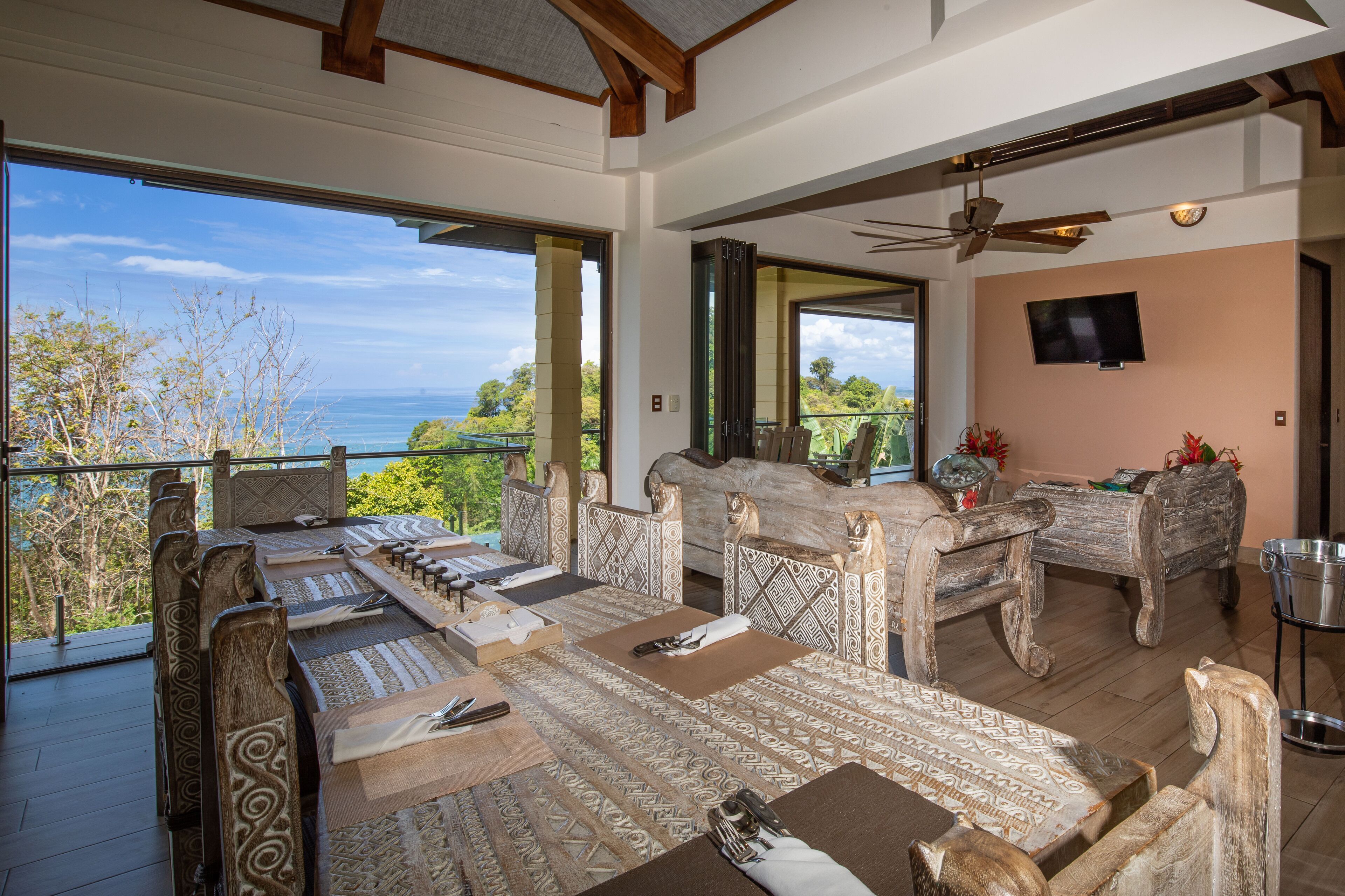 A spacious room with a long dining table, multiple chairs, and a television mounted on the wall.