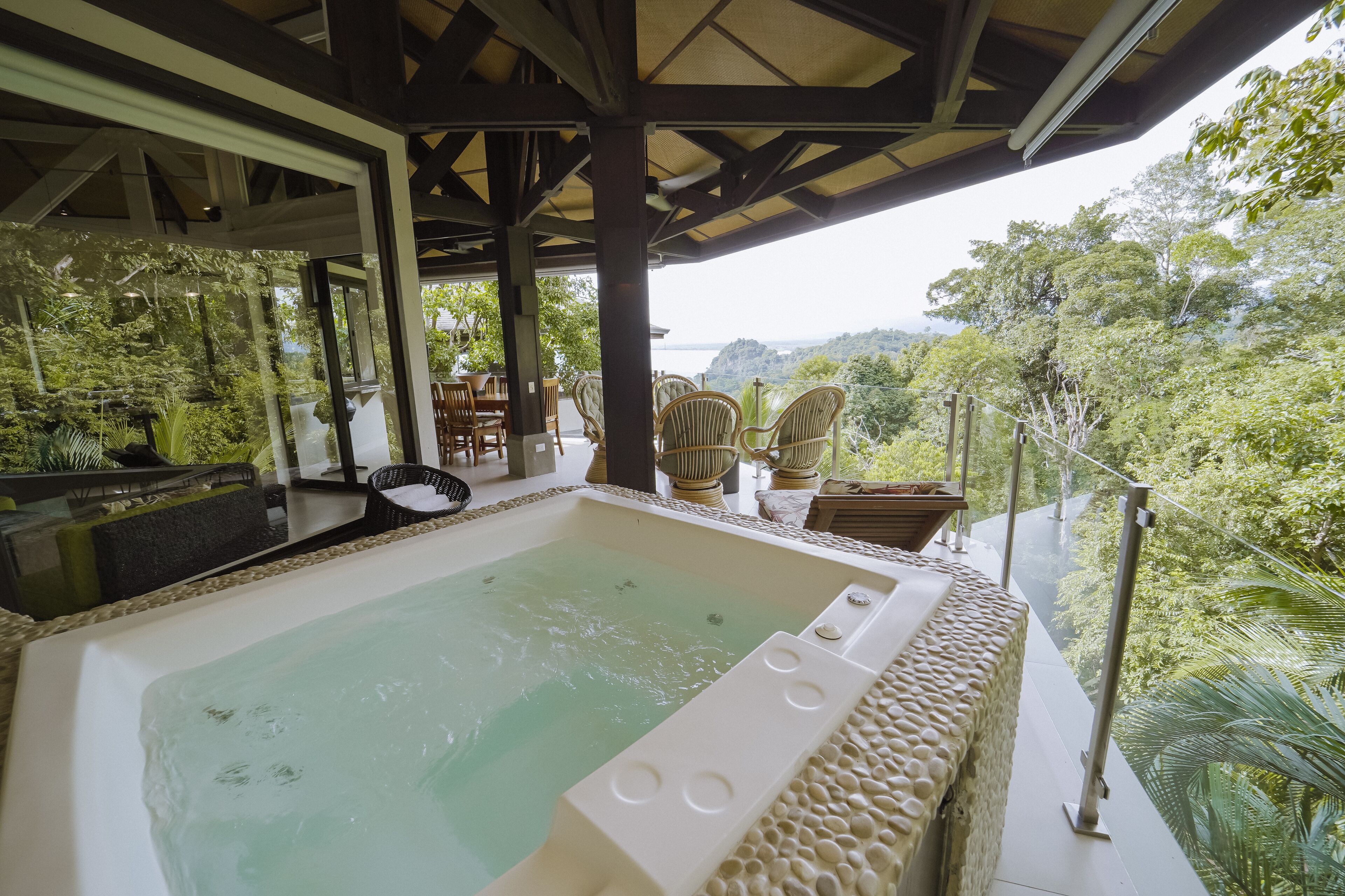 A hot tub with a view of a lush forest and a body of water.