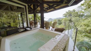 A hot tub with a view of a lush forest and a body of water.