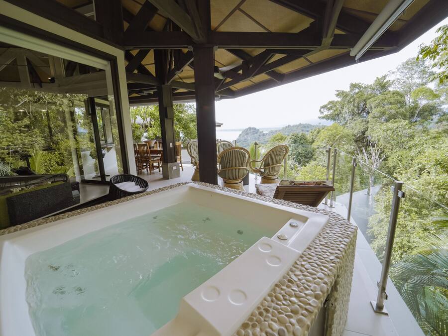 A hot tub with a view of a lush forest and a body of water.