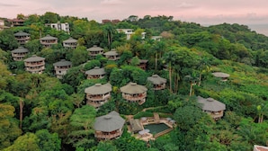Resort com vários edifícios no estilo de bangalôs, cercado por vegetação tropical densa.