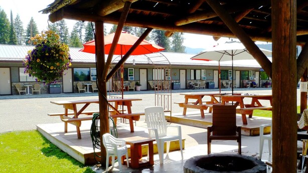 Un patio exterior con mesas de picnic, sillas y una chimenea.