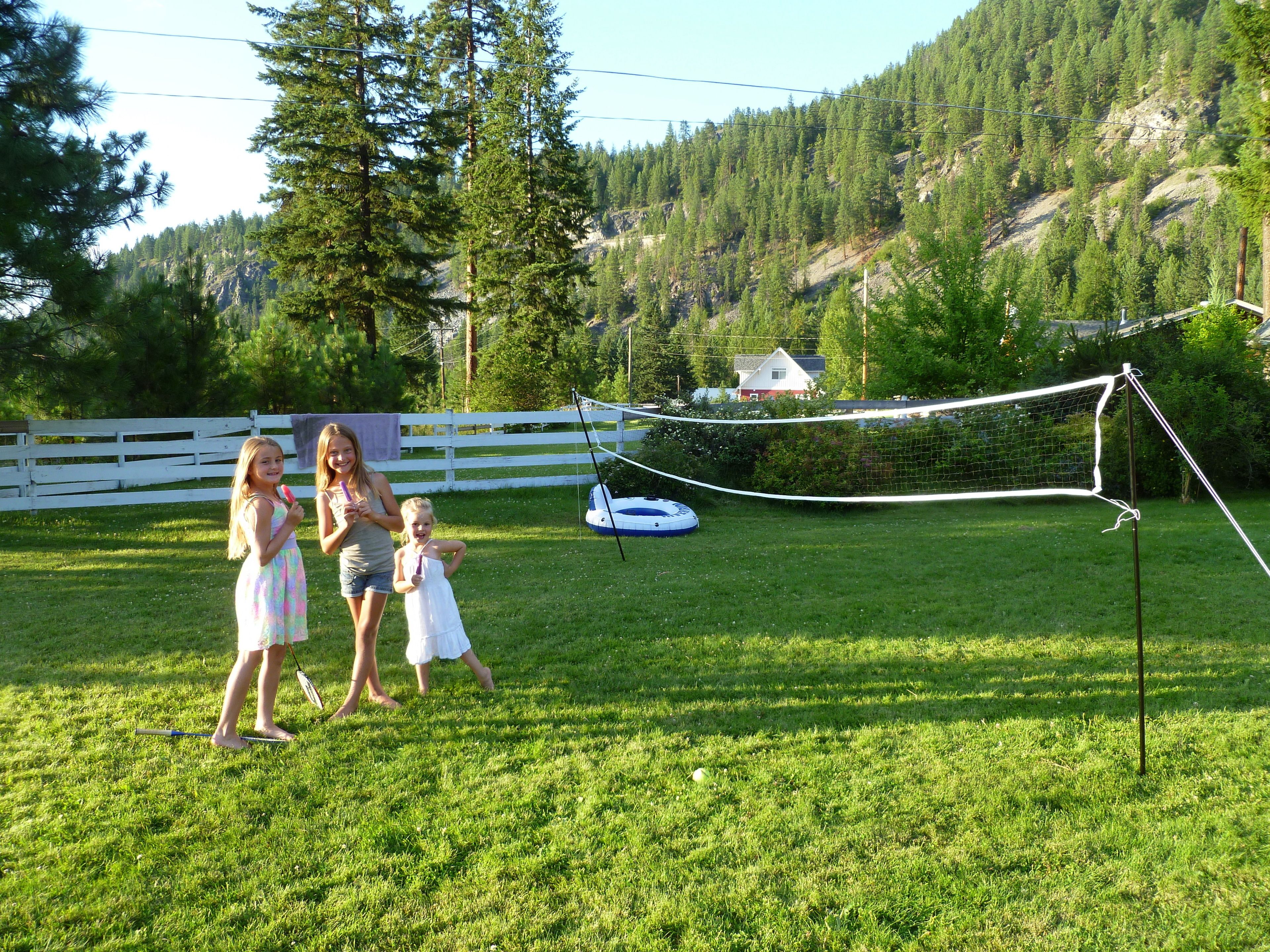 A grassy field with a white fence and a house in the background.