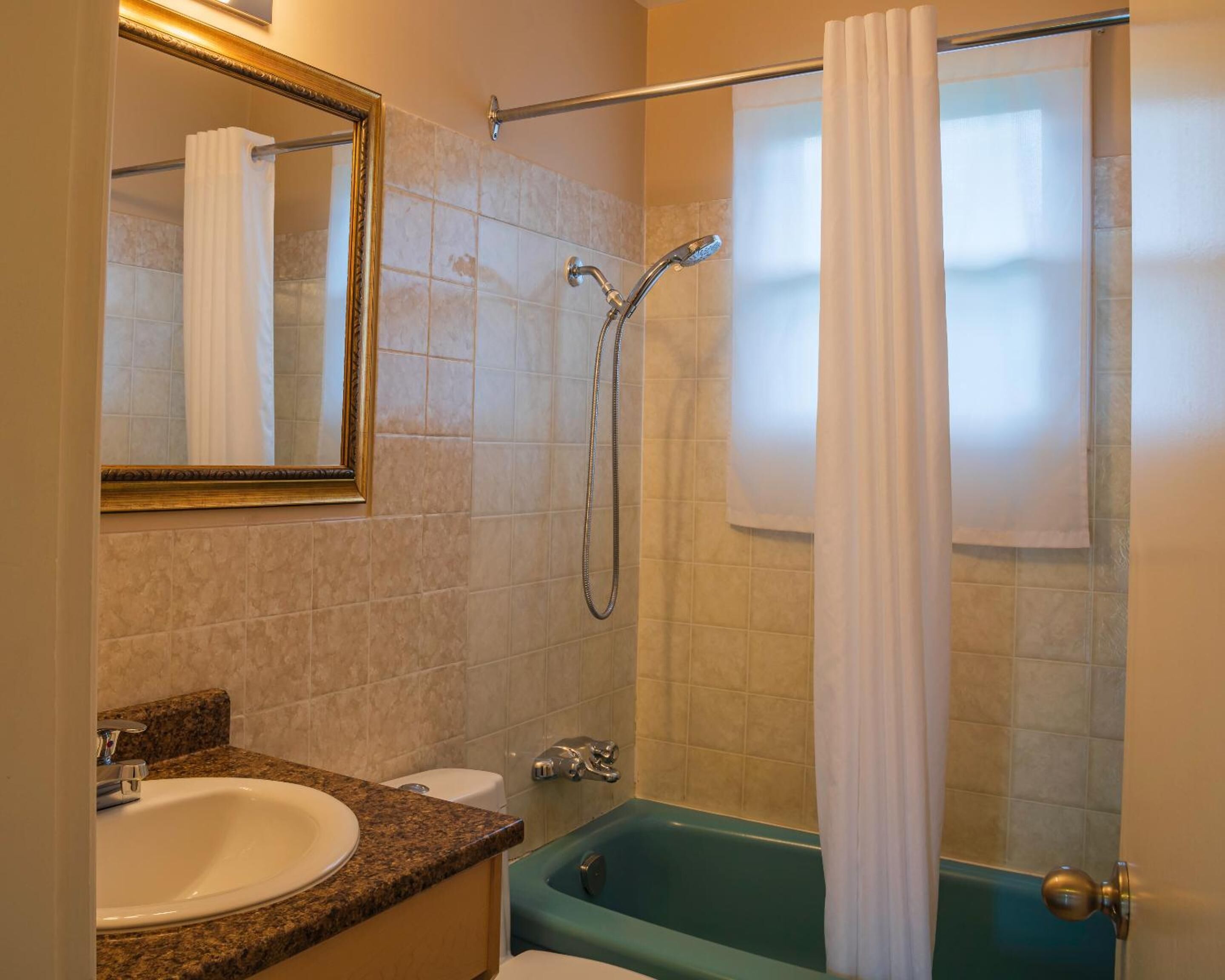A bathroom with a sink, toilet, bathtub, and a shower with a curtain.