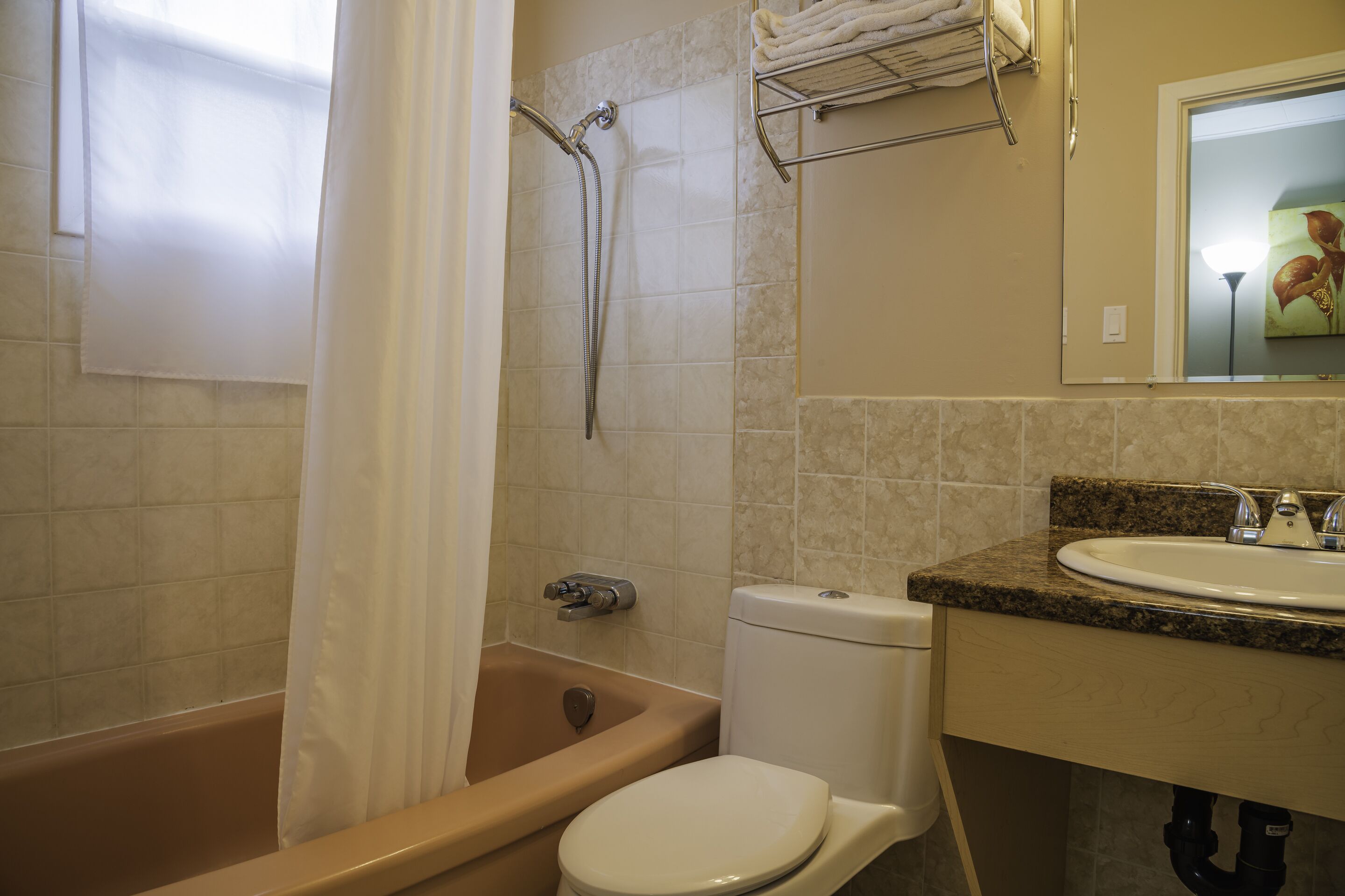 Une salle de bain équipée d’une baignoire, de toilettes, d’un lavabo et d’un rideau de douche.