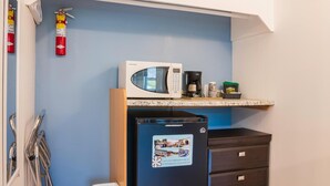 Una kitchenette compacta con microondas, cafetera y refrigerador.