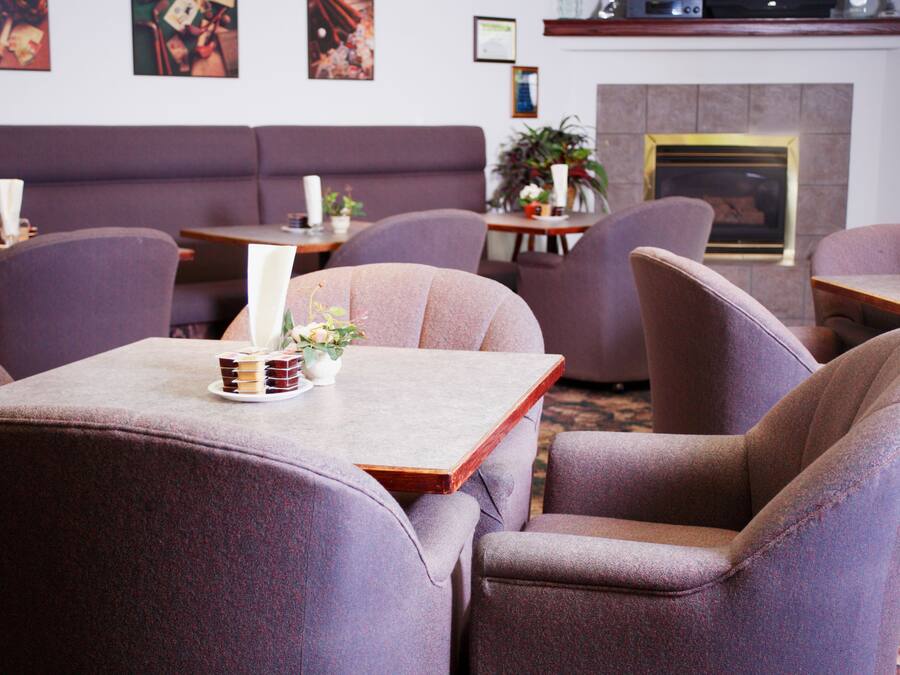 A restaurant with purple upholstered chairs and tables, a fireplace, and artwork on the walls.