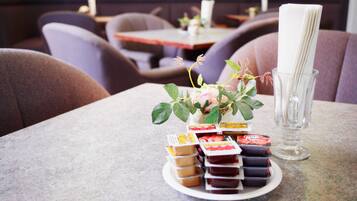 Een eettafel met een bord geassorteerde chocolade en een vaas met bloemen.