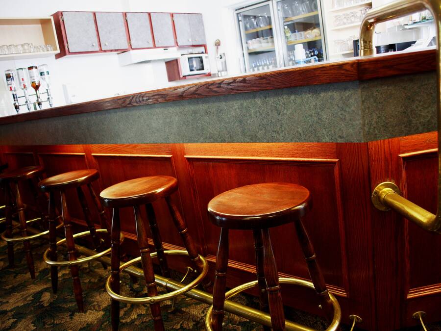 Una zona de bar con taburetes de madera y una barra.