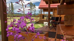 Une terrasse en bois avec des sièges d’extérieur et, au premier plan, des fleurs violettes.