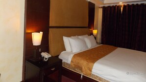 A hotel room with a bed, bedside lamps, a telephone, and a dark curtain. - MO2 Westown Hotel Bacolod - Mandalagan (Bacolod)