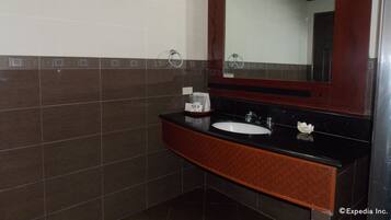 A bathroom with a black countertop, white sink, and a large mirror.