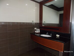Un baño con encimera negra, lavabo blanco y un espejo grande.