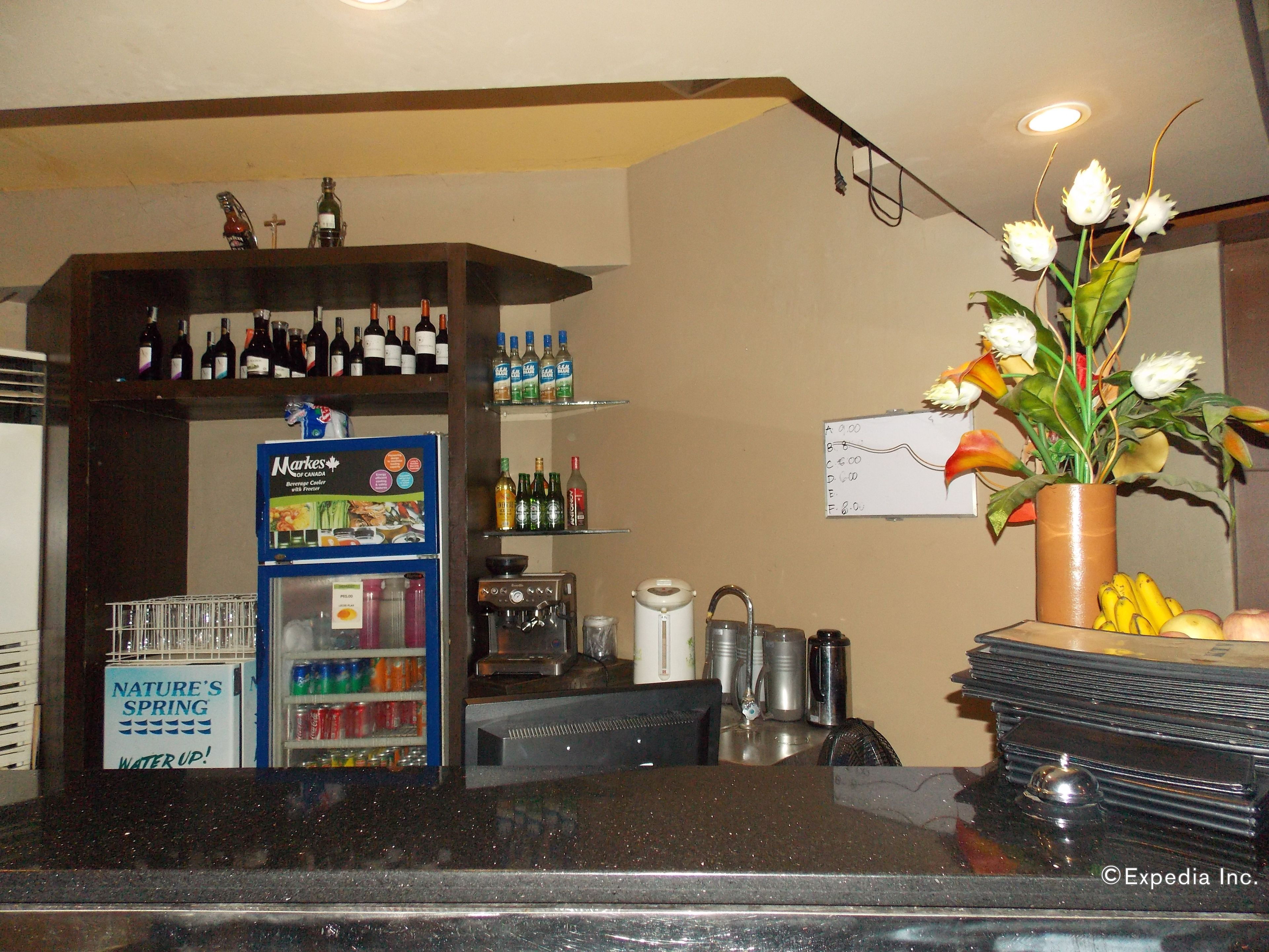 A bar area with shelves of bottled beverages, a coffee machine, and a flower arrangement.