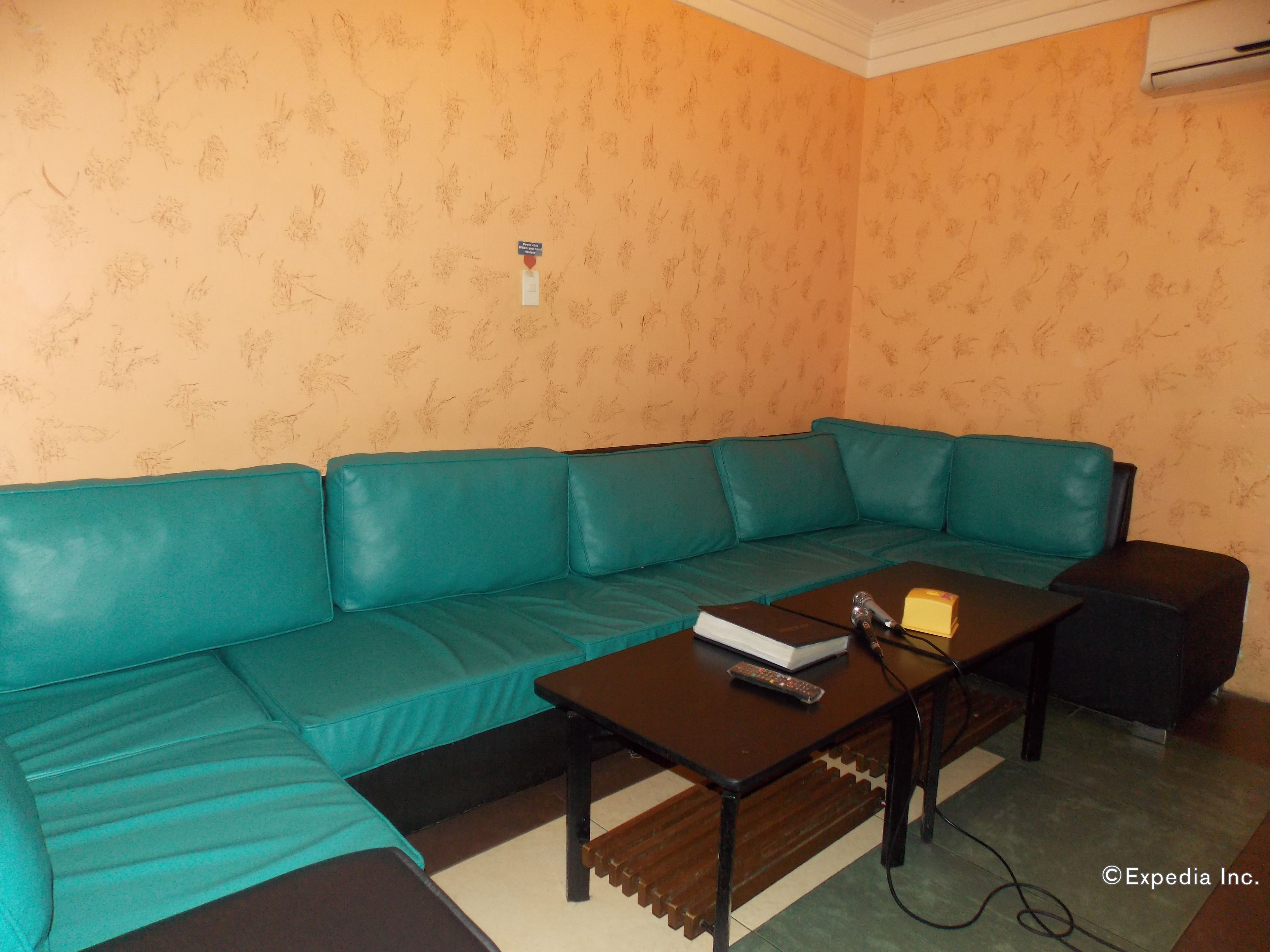 A teal sofa, a wooden coffee table, and a remote control on the table.