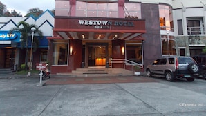 The Westown Hotel with a prominent entrance, a parking sign, and a parked SUV. - MO2 Westown Hotel Bacolod - Mandalagan (Bacolod)