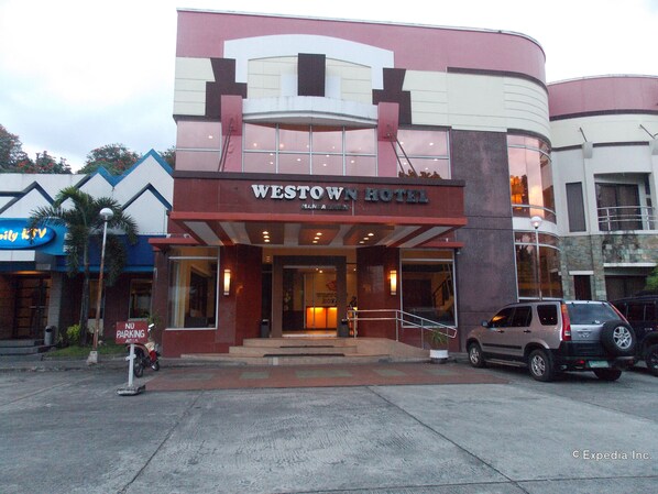 Hotel Westown con una entrada destacada, un cartel de estacionamiento y un SUV estacionado.
