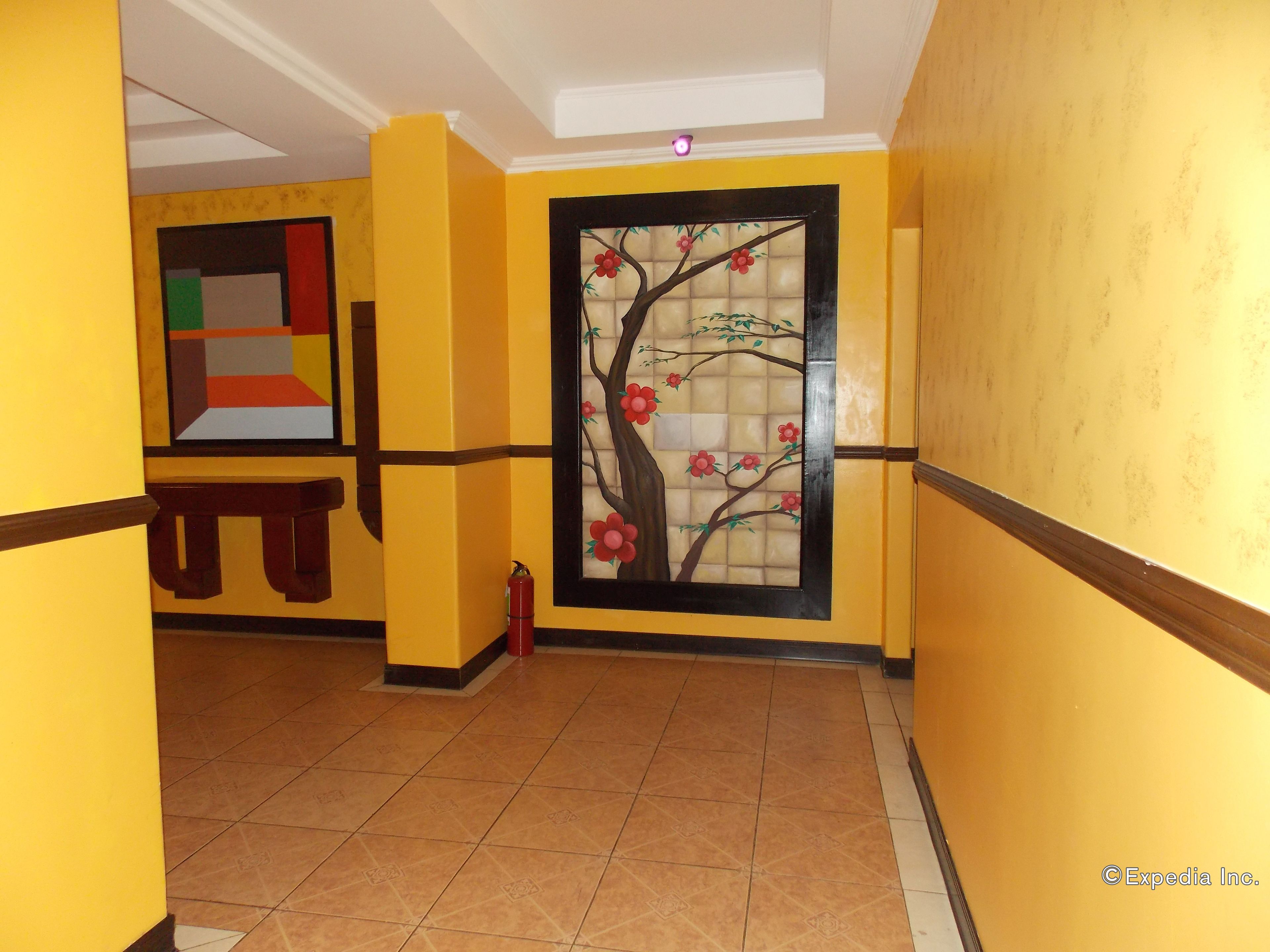 A hallway with yellow walls, a tiled floor, and a decorative glass panel with a tree and flowers.