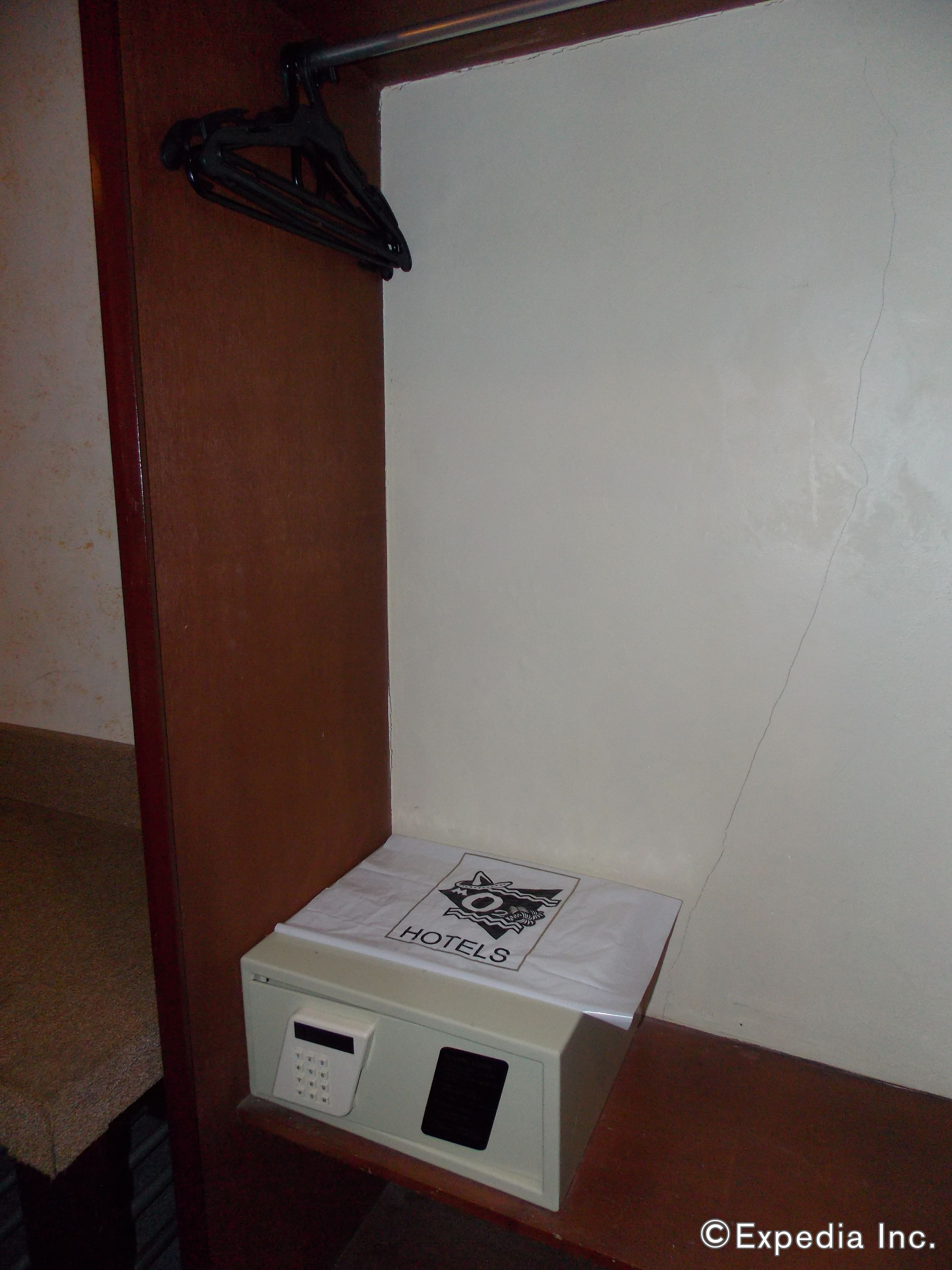 A hotel room with a white wall, a wooden door, and a small white box labeled "HOTELS" on the floor.