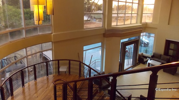 A spacious interior with a high ceiling, large windows, and a wooden staircase. - MO2 Westown Hotel Bacolod - Mandalagan (Bacolod)
