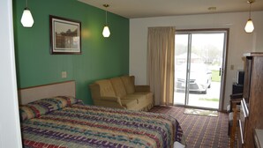 Habitación de hotel con cama, sofá, televisión y vistas al exterior.