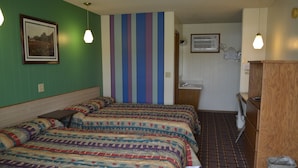 Habitación de hotel con dos camas, baño y una pequeña zona de escritorio.