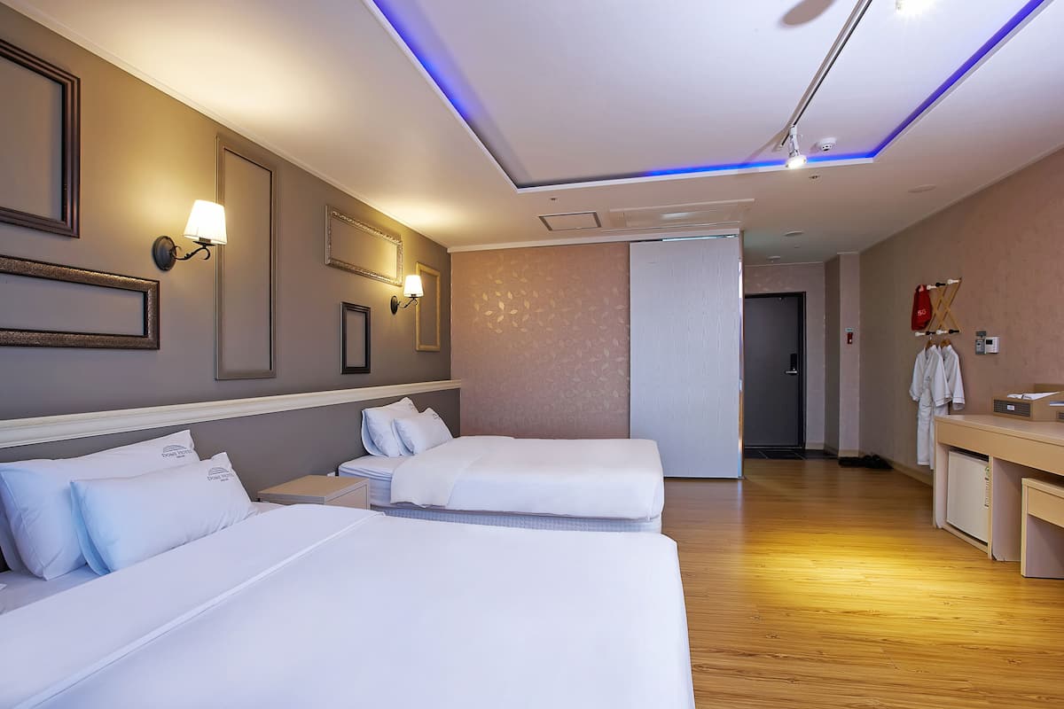 A hotel room with two beds, a desk, a mirror, and a wardrobe.