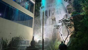 Edifício com vários níveis, uma cascata e vista para uma paisagem rochosa.
